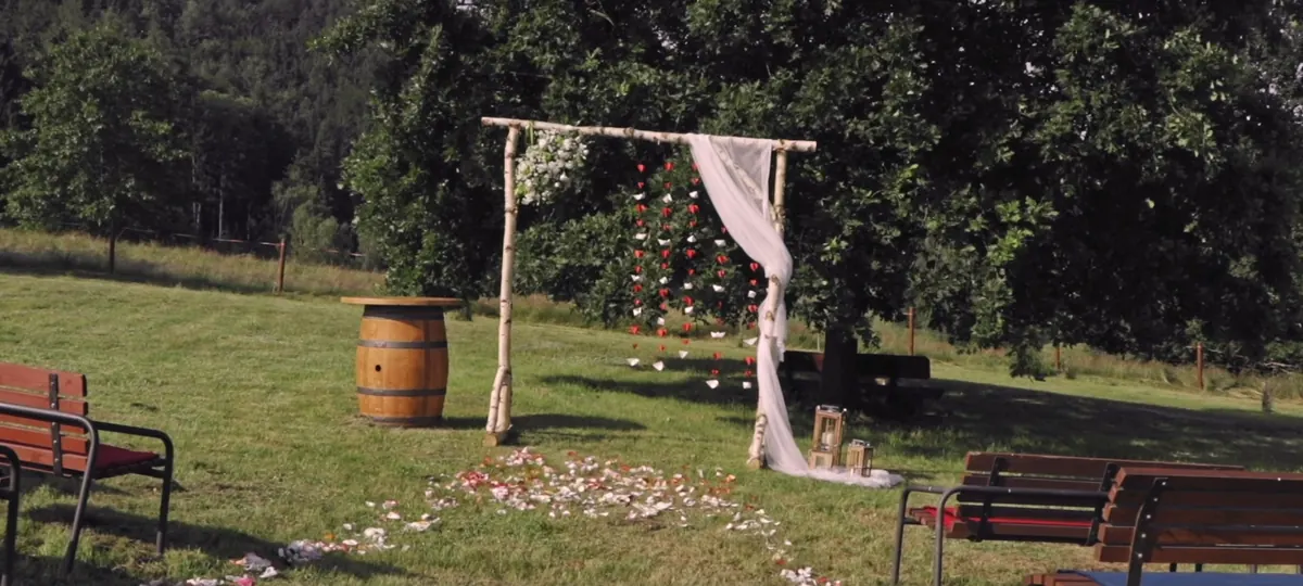 Březová obřadní brána s látkou, sudem a lavicemi v zahradě