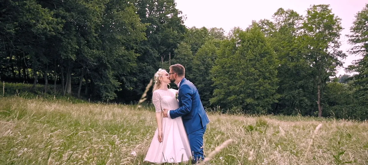 Novomanželé ve vysoké trávě na okraji lesa